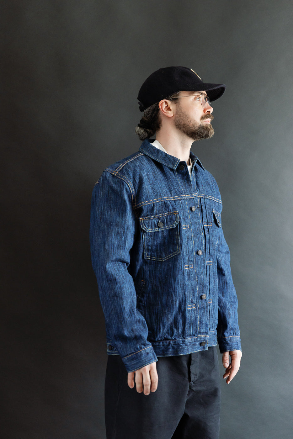 Bearded man in profile wearing the 6225-L - 14.5oz Light Waterfall Selvedge Type II Jacket in indigo; a streamlined denim jacket with chest and hand-warmer pockets, showcasing a textured Japanese selvedge slub denim.