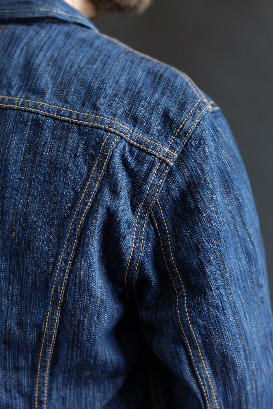 Close-up of the 6226-L - 14.5oz Light Waterfall Selvedge Type III Jacket's back shoulder, highlighting the intricate chainstitch construction and textured Japanese selvedge denim.