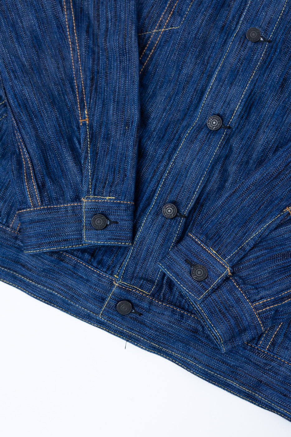 Close-up of the 6226-L - 14.5oz Light Waterfall Selvedge Type III Jacket in Indigo, showcasing the hem, button placket, sleeve cuffs with metal snap buttons, and contrasting orange topstitching.