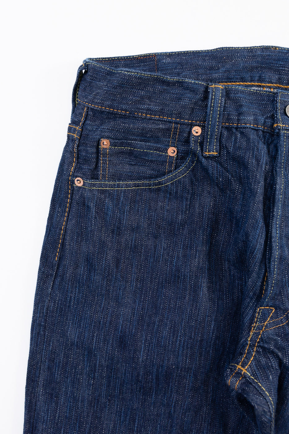 Close-up of the front right waist and pocket of dark blue selvedge denim jeans.