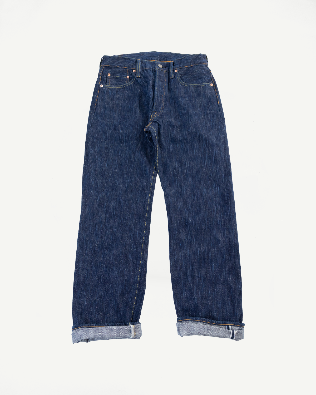 Front view flat lay of dark blue selvedge denim jeans with cuffed hems.