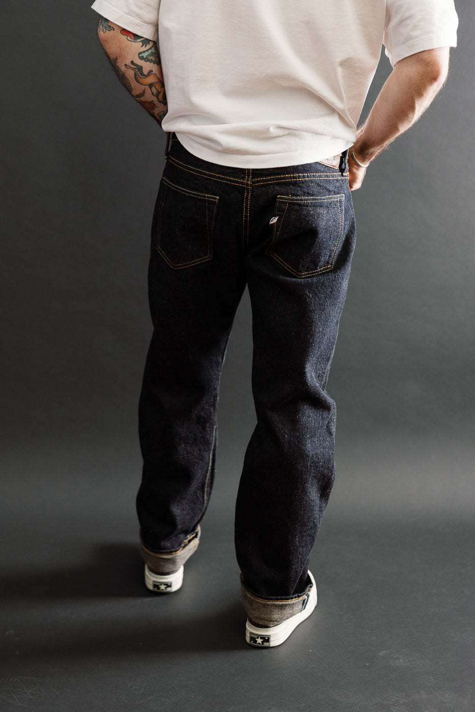 Back view of dark indigo selvedge denim jeans worn by a male model, 5'9