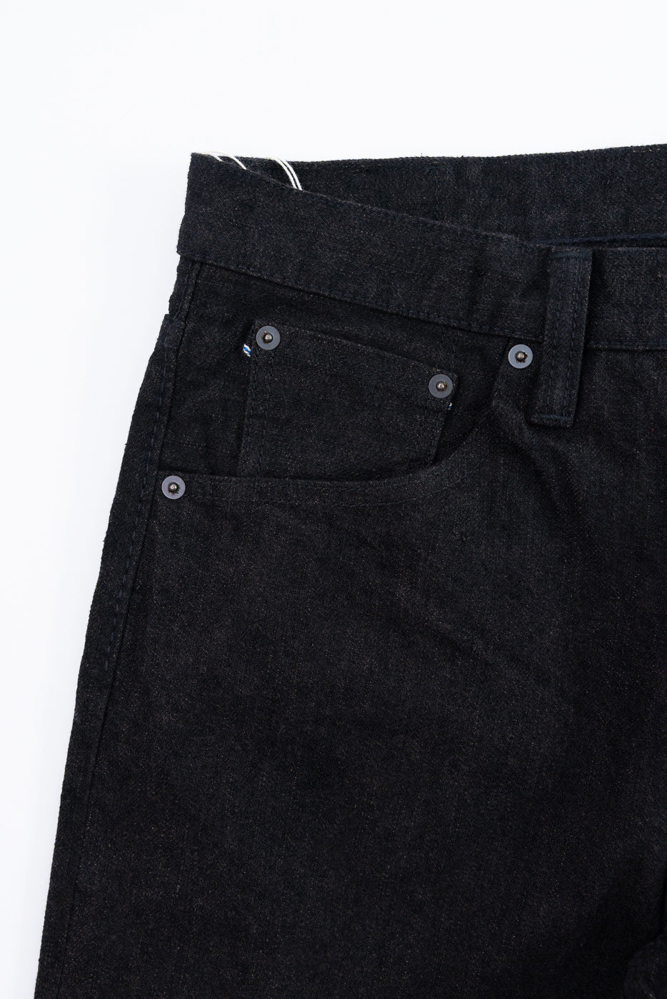 Close-up front view of dark selvedge denim jeans, showcasing button details and fabric texture