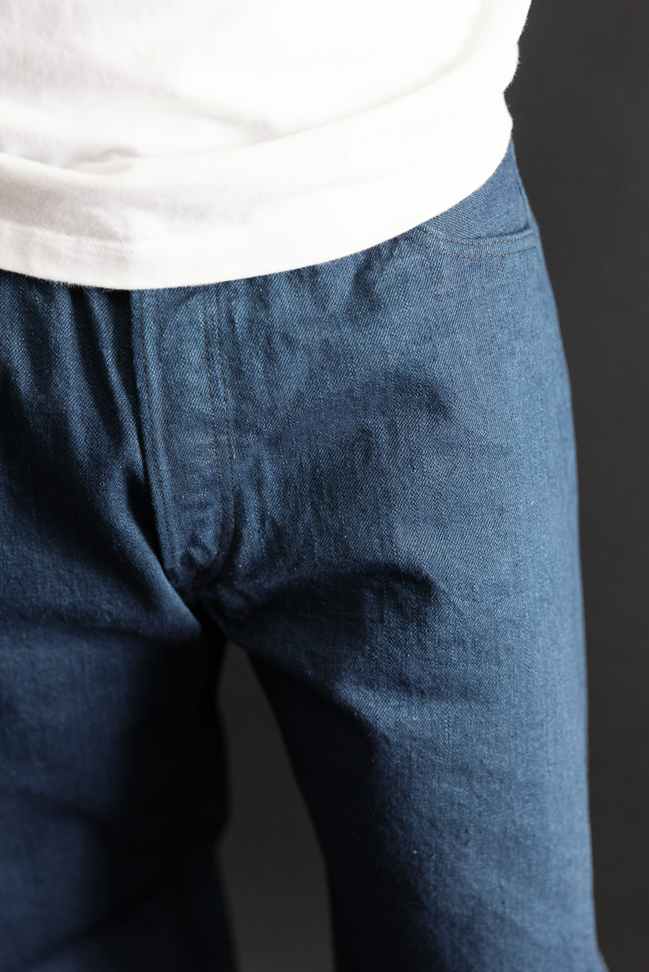 Close-up front view of navy selvedge denim texture on a male model, 5'9