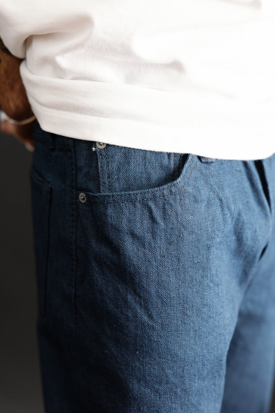 Close-up of front right pocket and button on navy selvedge jeans, worn by 5'9