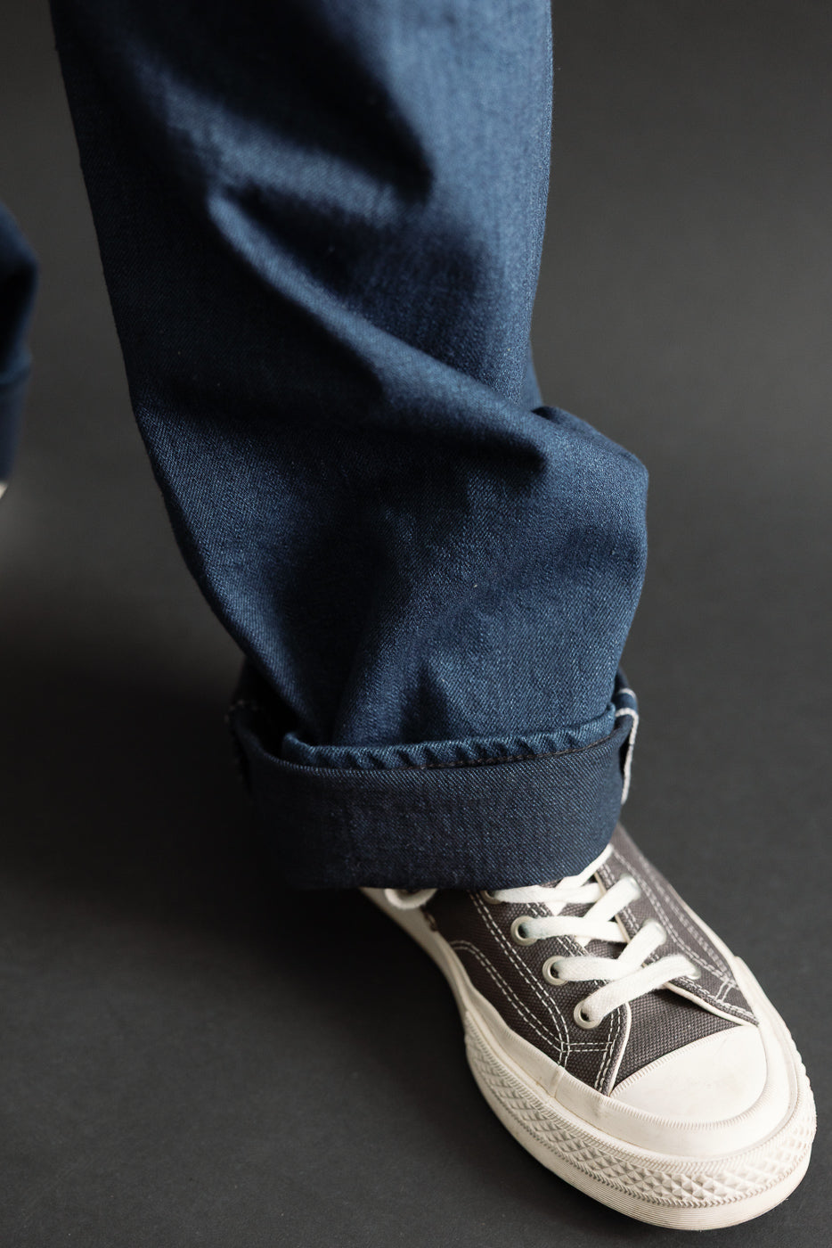 Close-up of cuffed hem on navy selvedge denim worn by a 5'9