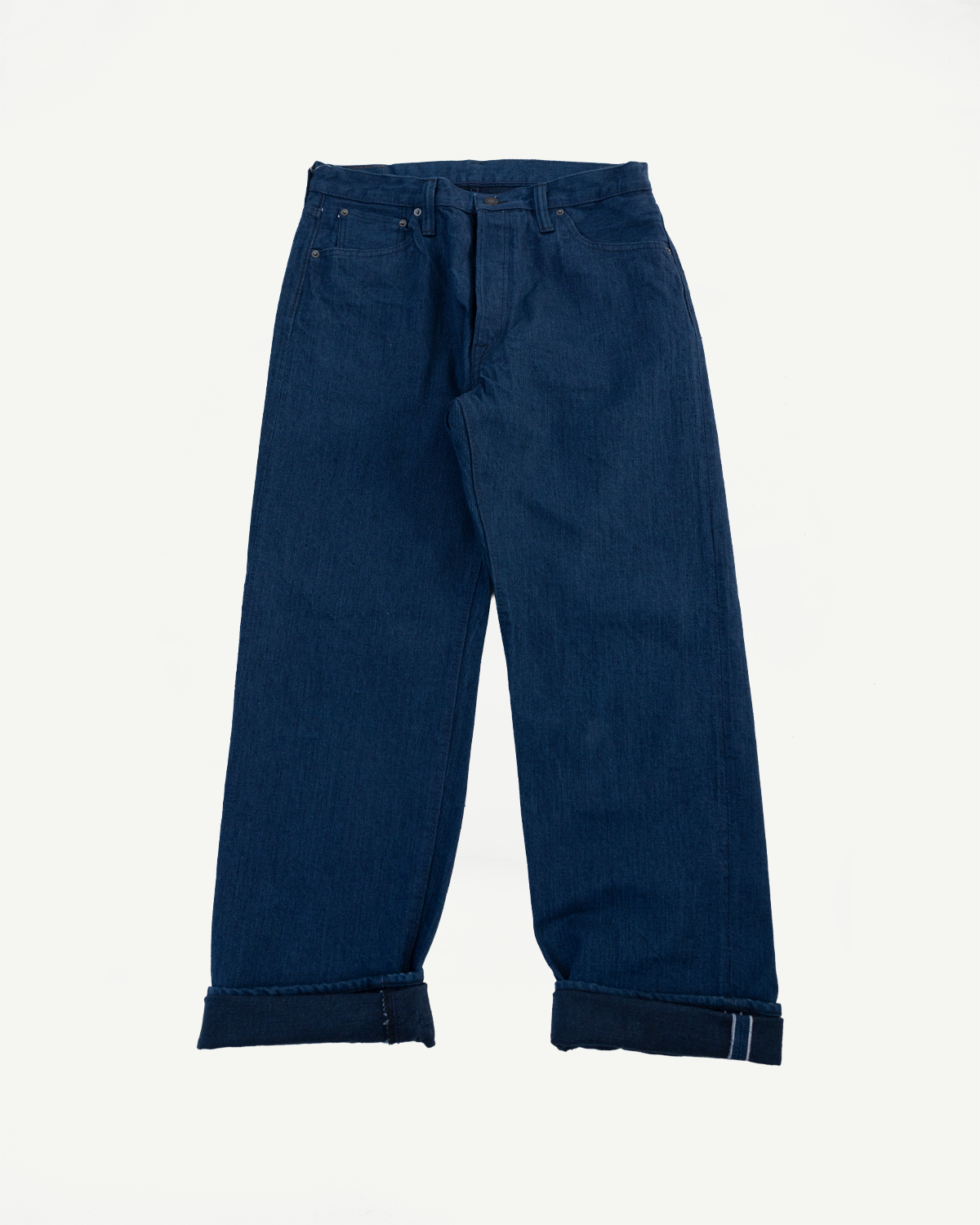 Front view flat lay of dark indigo denim jeans with cuffed hems on a white background.