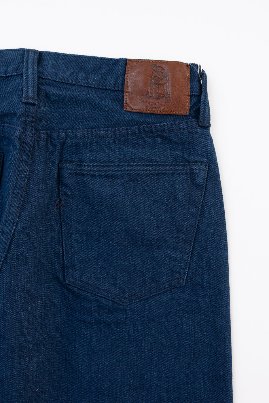 Close-up of the back of blue denim jeans showing a leather patch and back pocket.