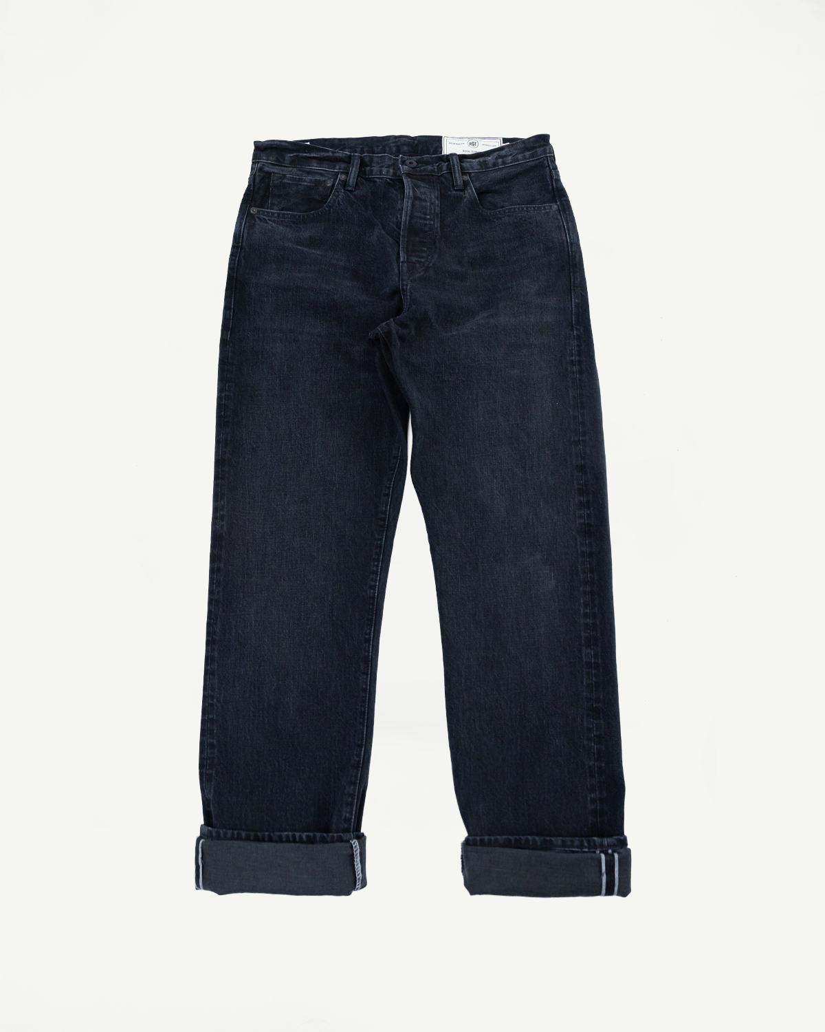 Flat lay front view of dark selvedge denim jeans with cuffed hems, visible waistband tag, and classic 5-pocket design
