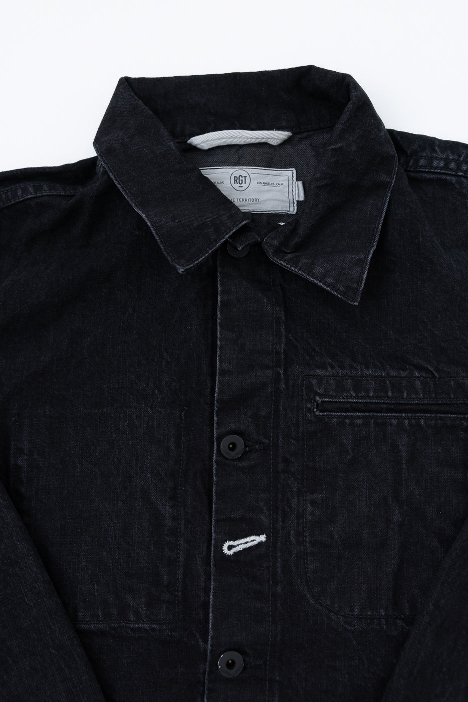 Close-up front of black denim jacket, showing collar, buttons, chest pocket, and fabric texture.