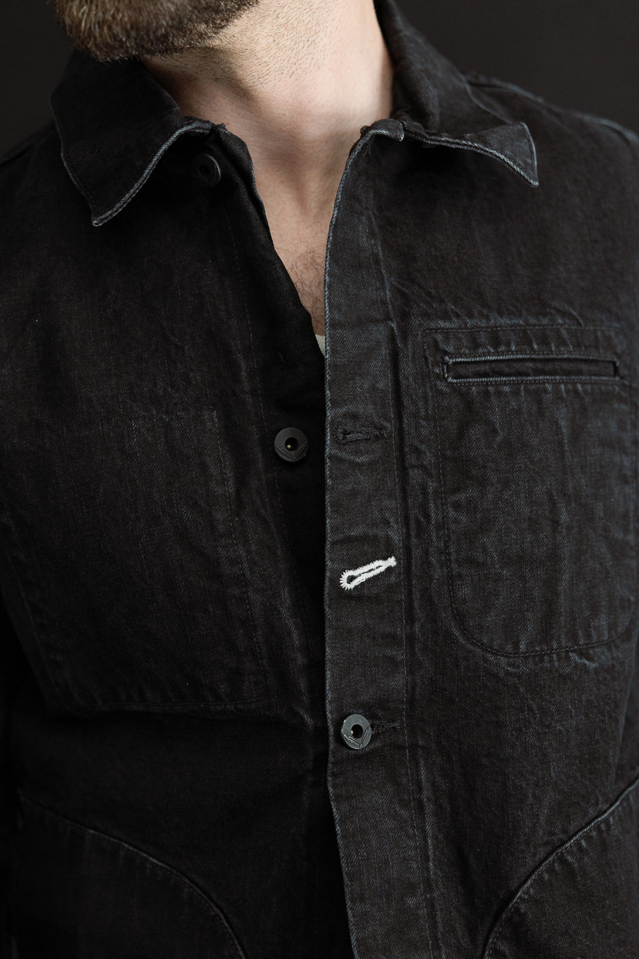 Close-up front of black denim jacket on male model, 5'9