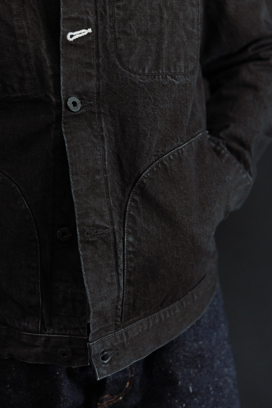 Close-up front view of black denim jacket on male model 5'9