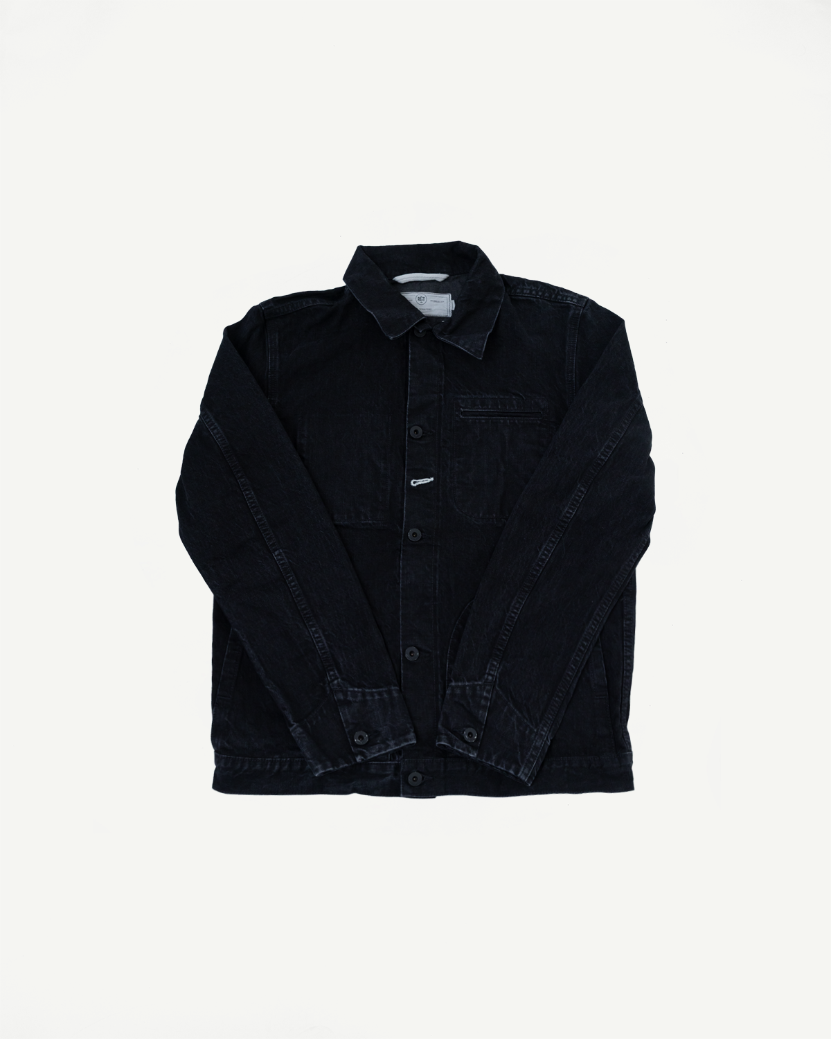 Flat lay front view of black denim supply jacket, showing collar, buttons, left chest pocket, and cuff details.
