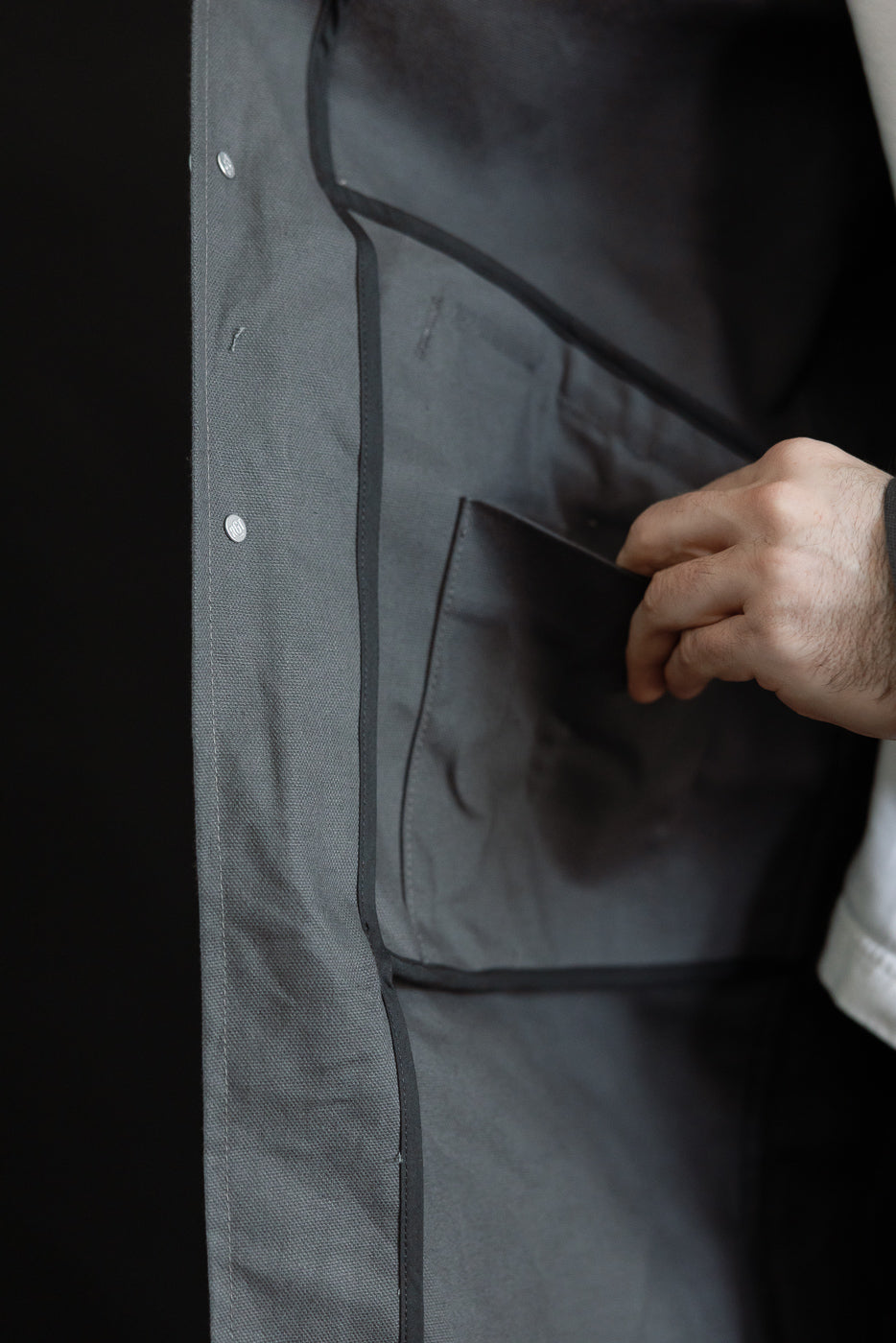 Close-up of the inside left pocket of a grey waxed canvas trench coat, showing fabric texture and seam details.