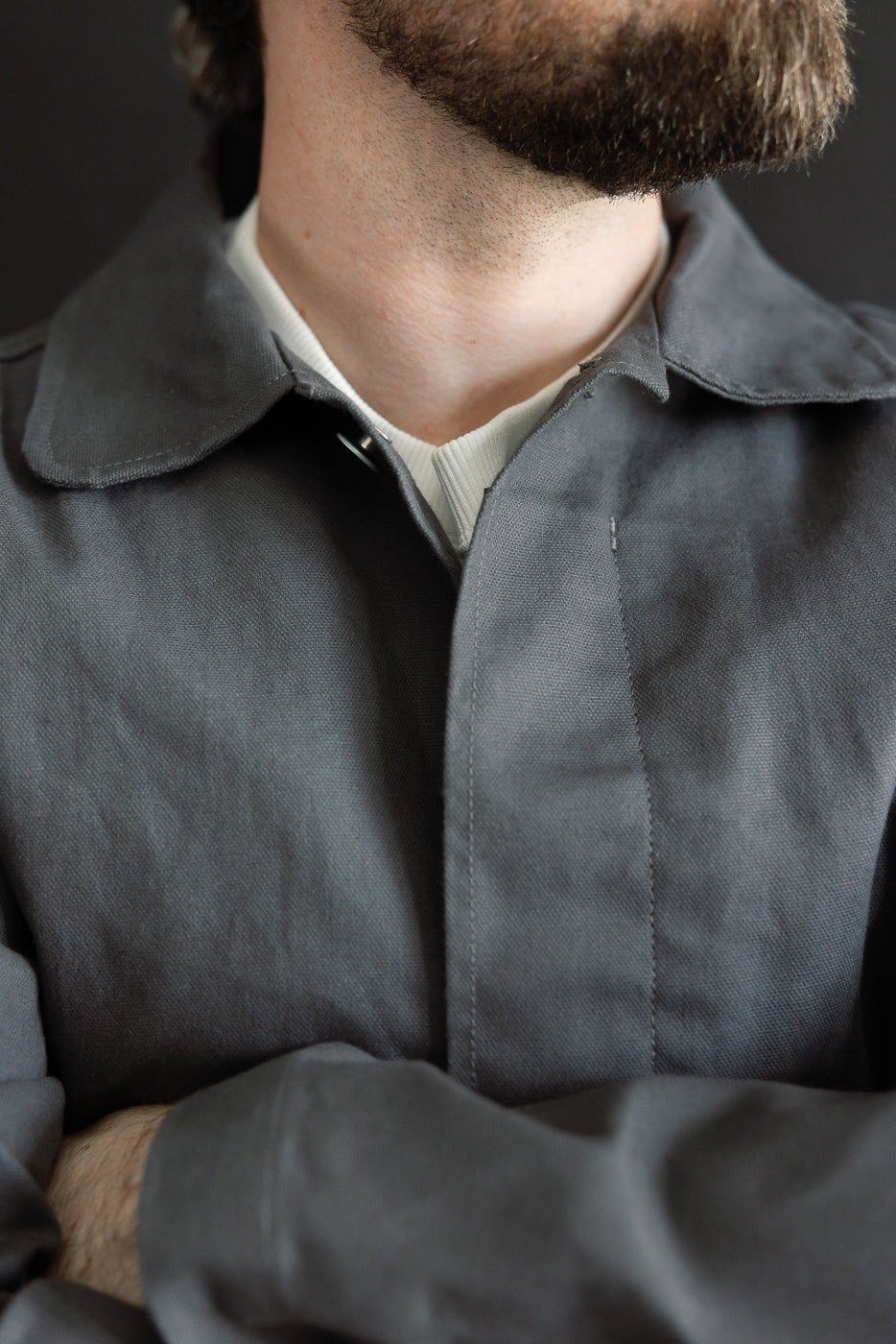 Close-up front view of grey dry waxed canvas trench coat collar and chest on male model, 5'9
