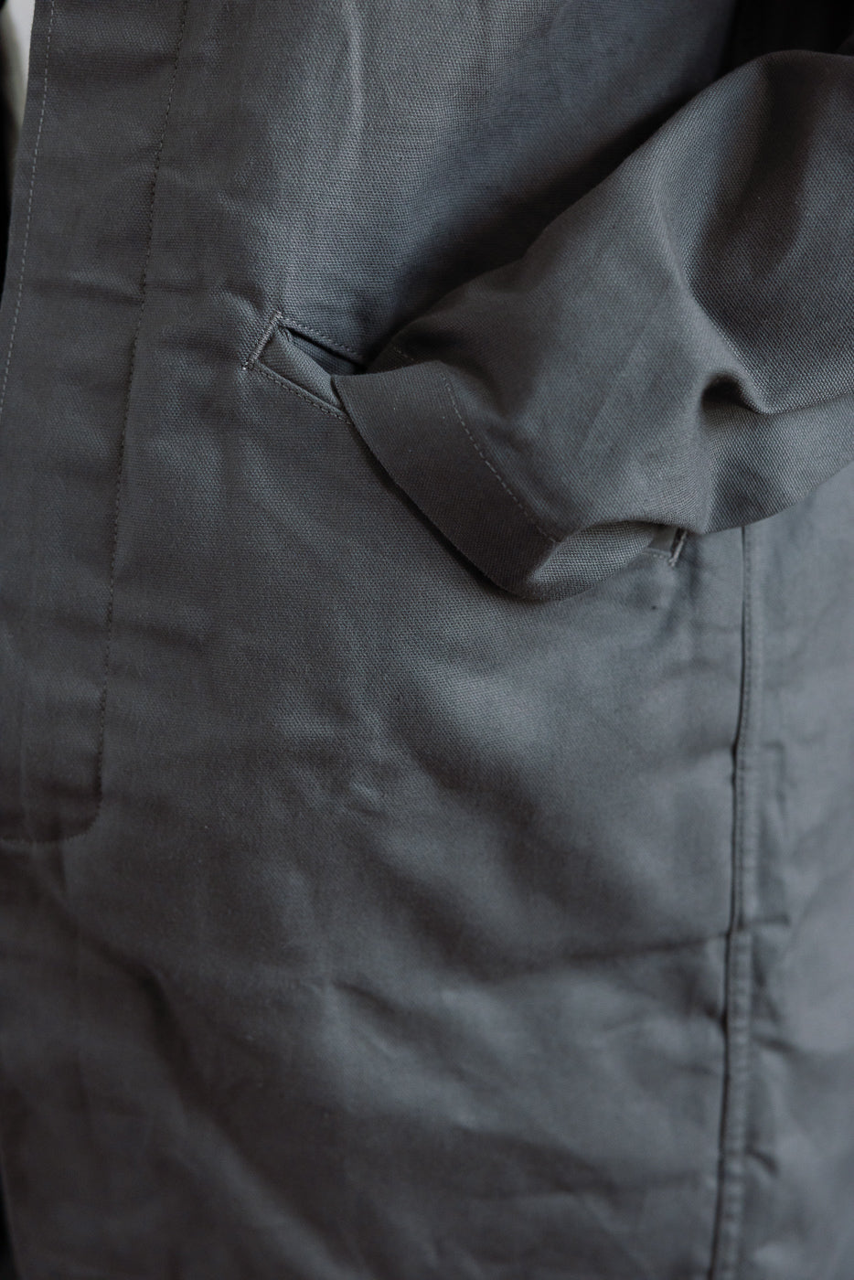 Close-up of men's grey dry waxed canvas trench coat front pocket and fabric texture