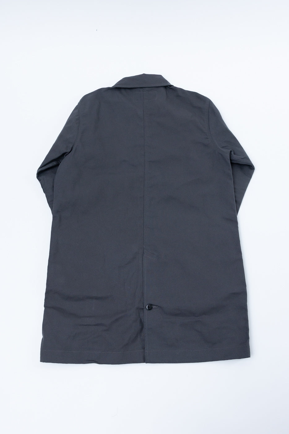 Flat lay of grey trench coat, back view, showing straight hem and collar details.