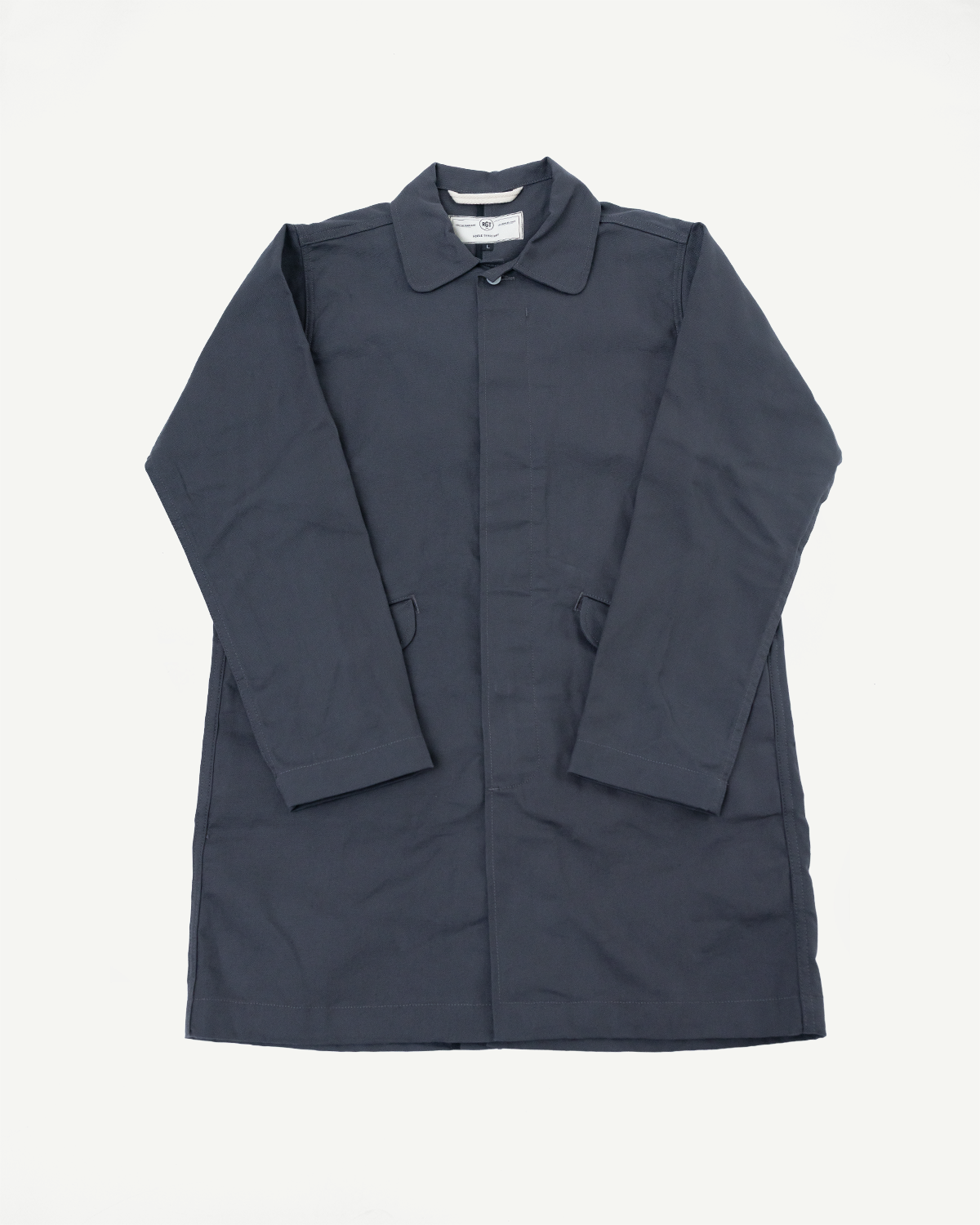 Flat lay, front view of grey trench coat in dry waxed canvas, showing collar and pockets.