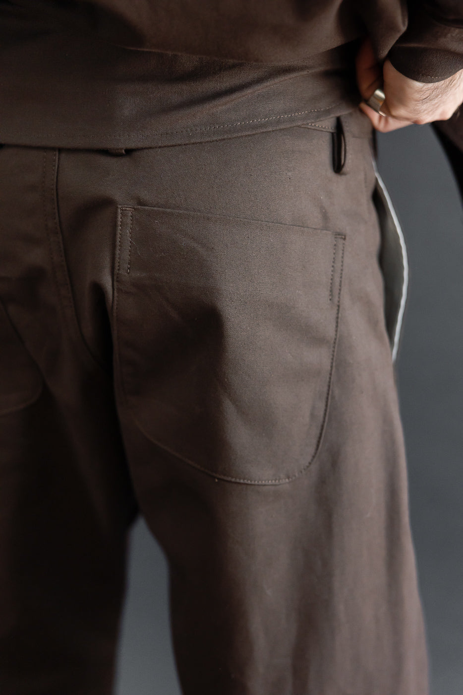 Close-up of back right pocket on brown trousers worn by male model, 5'9