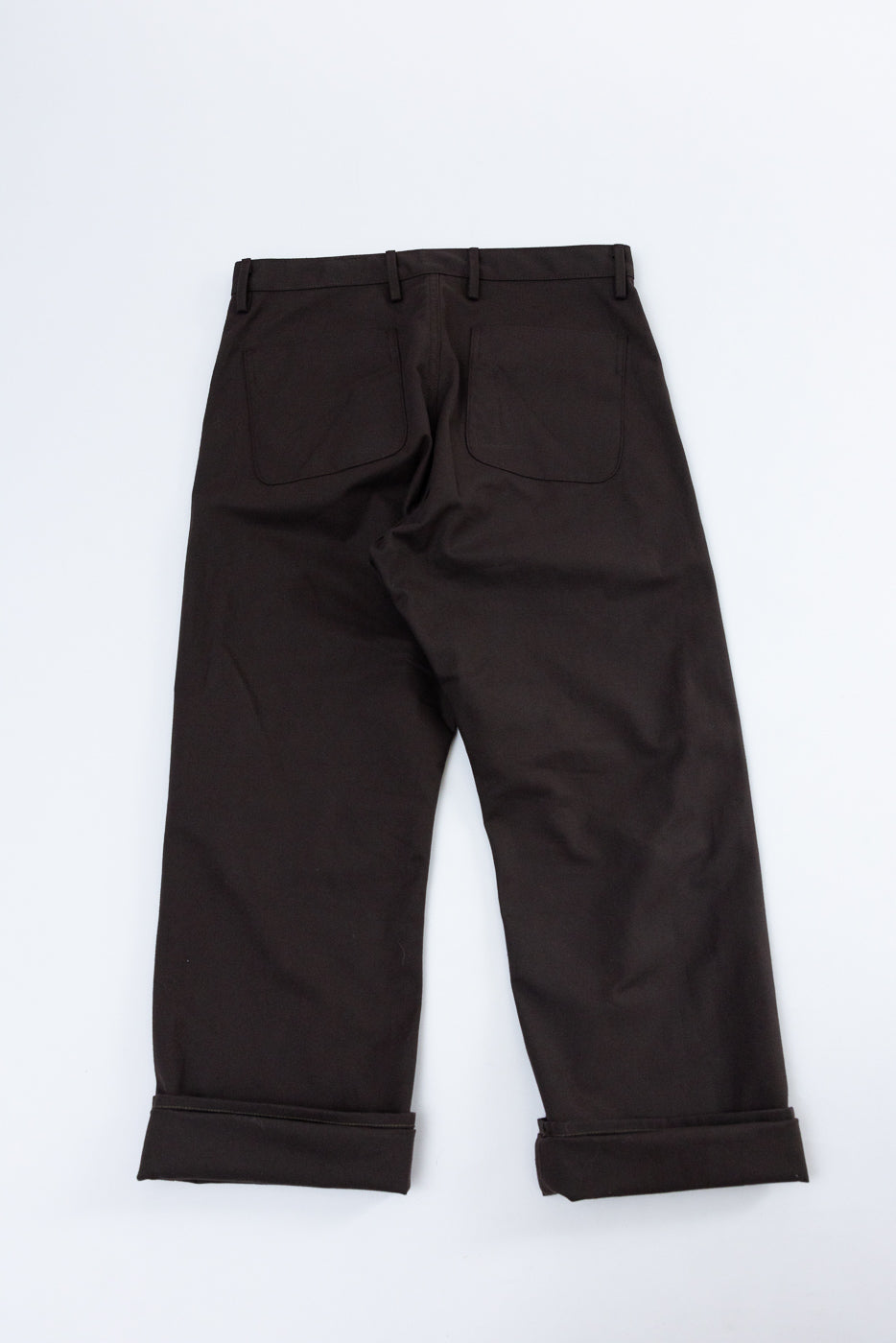 Back view flat lay of dark brown casual trousers with cuffed hems.