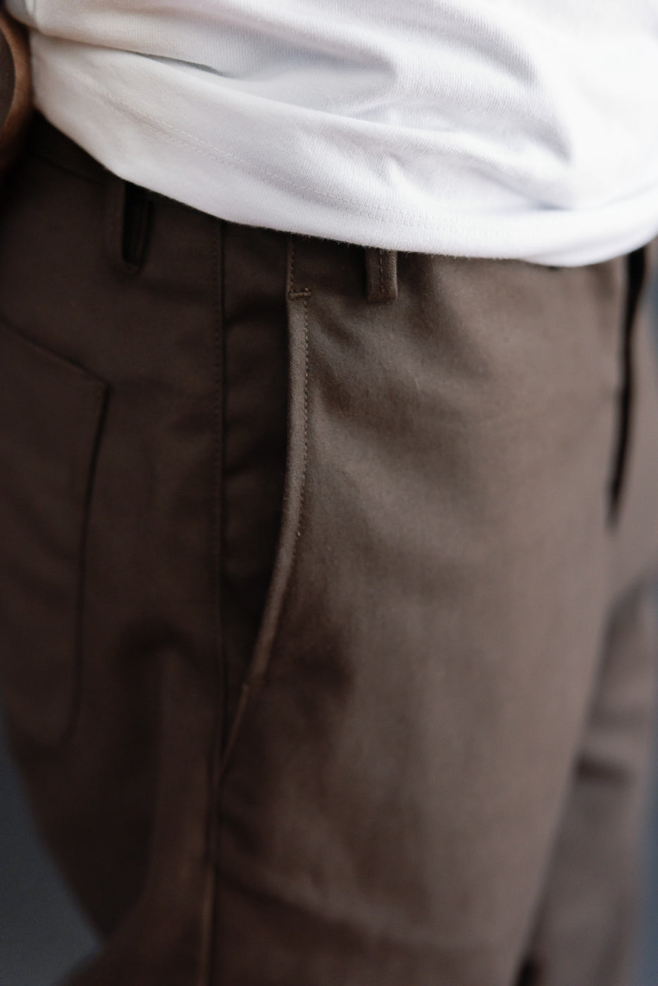 Close-up of the front right waist and pocket of brown trousers on a 5'9