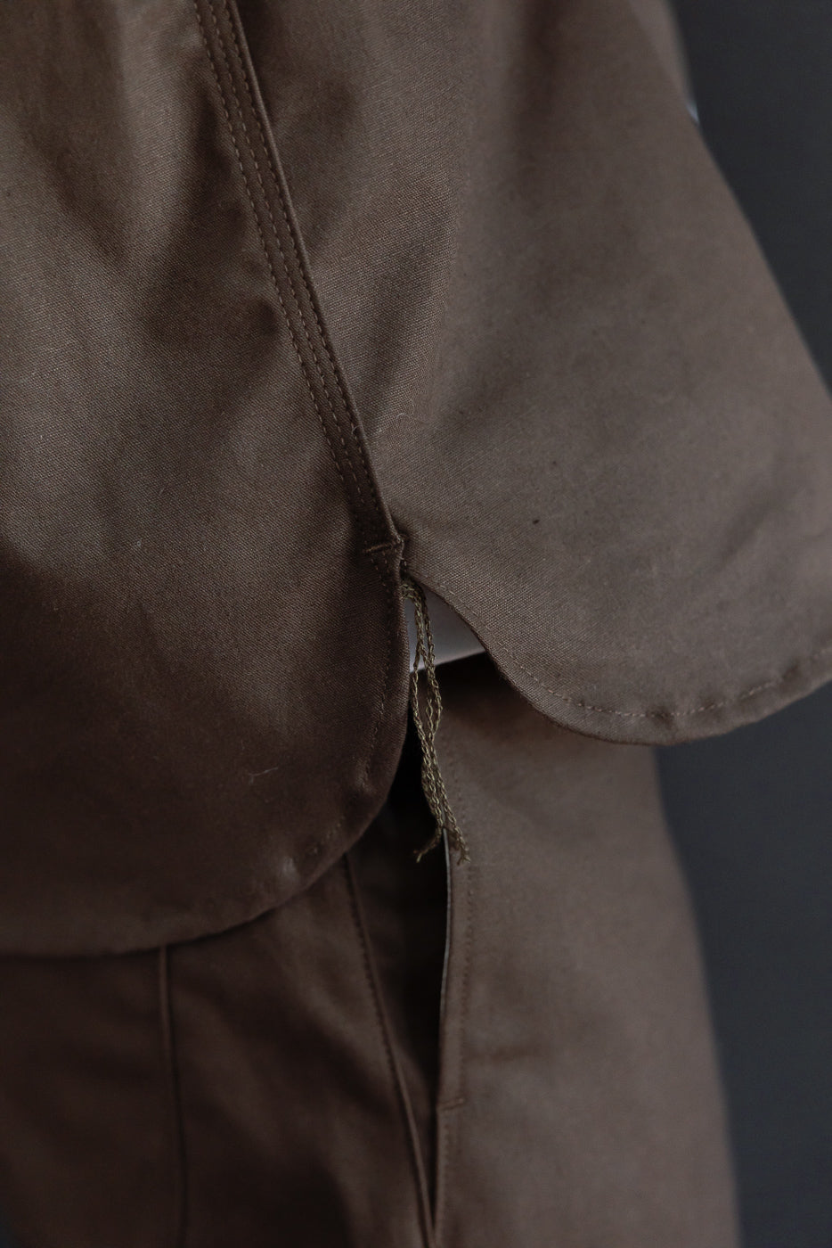 Close-up of the side hem and stitching on a brown fabric garment.