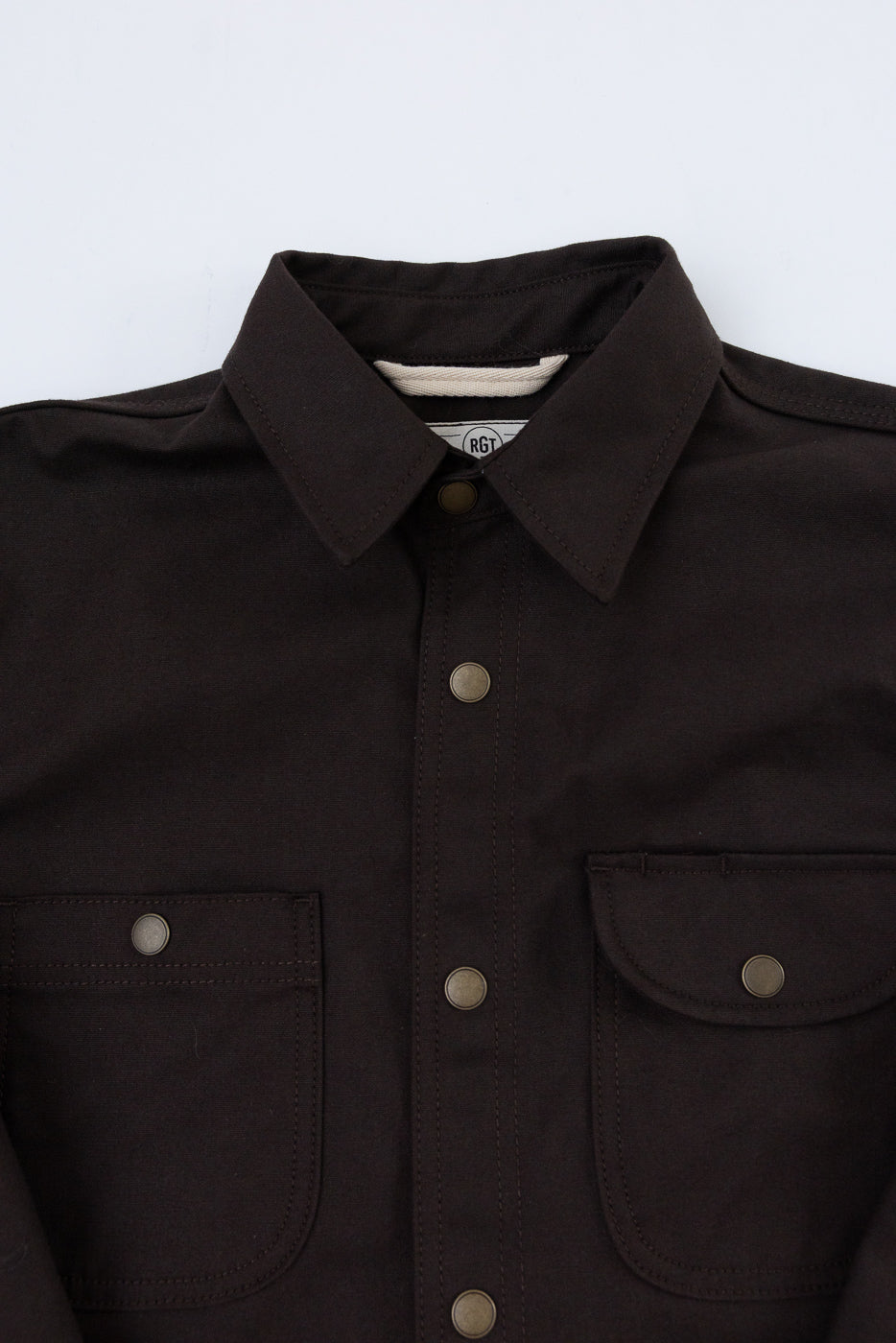 Close-up front view of a dark brown button-up shirt showing collar, buttons, and chest pockets.