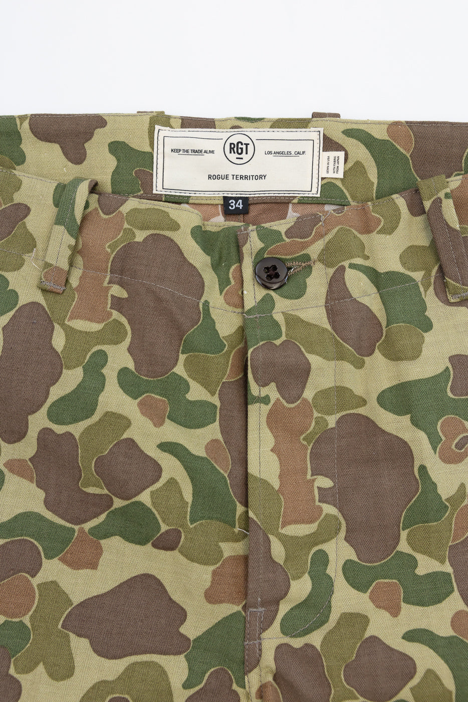 Close-up front of camo pants with RGT tag, size 34, button fly, and fabric texture details