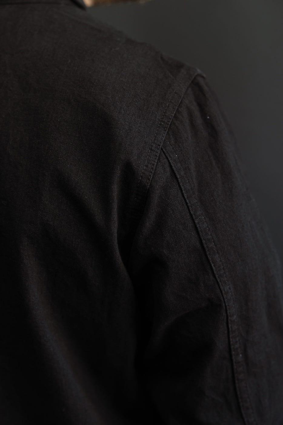 Close-up back shoulder view of black shirt on male model, 5'9