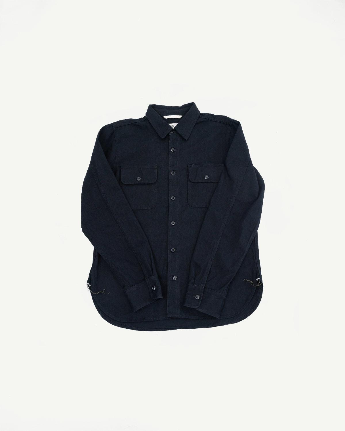 Front view of dark navy button-up shirt with two chest pockets, long sleeves, and curved hem