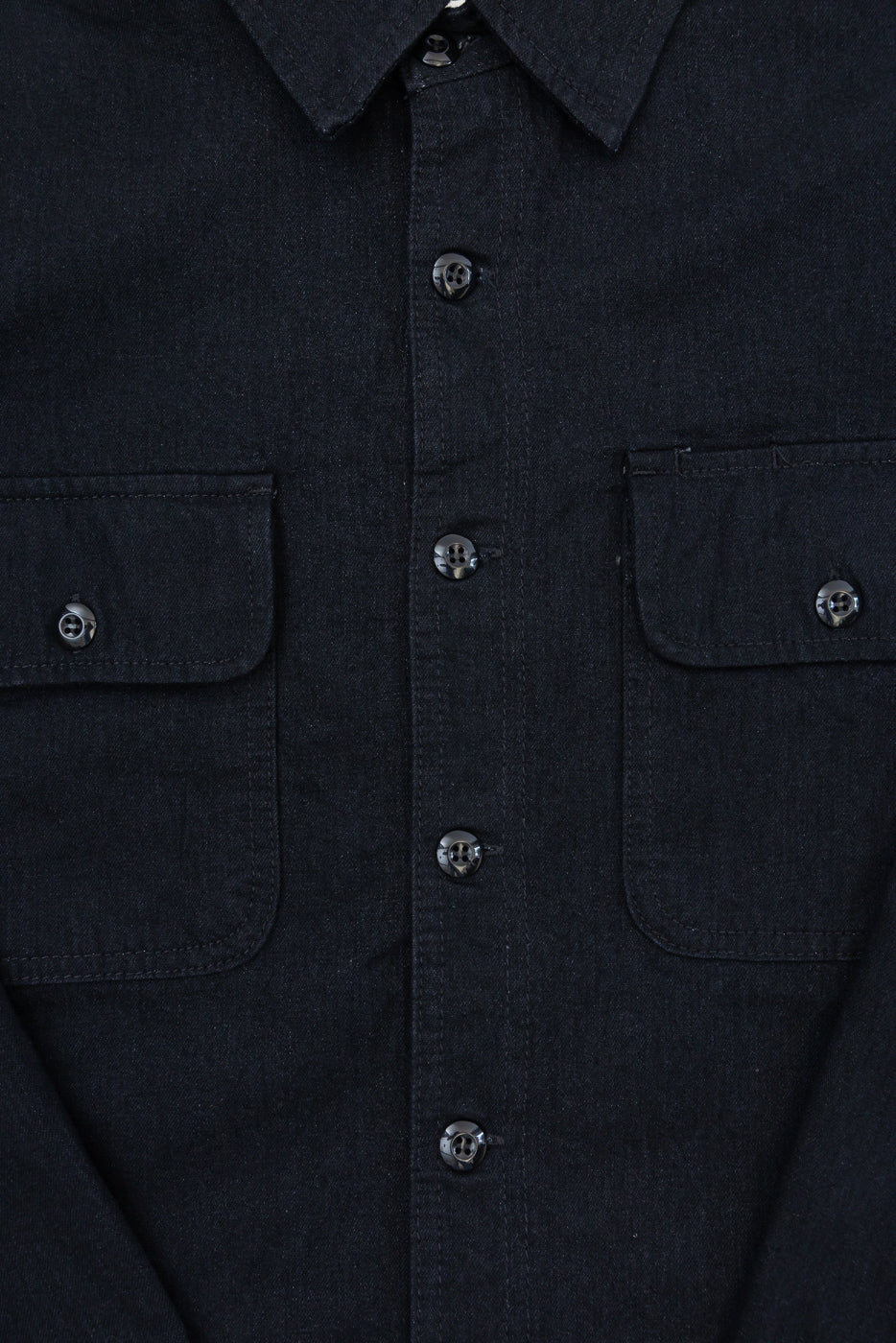 Close-up front view of dark denim shirt with button details and chest pockets