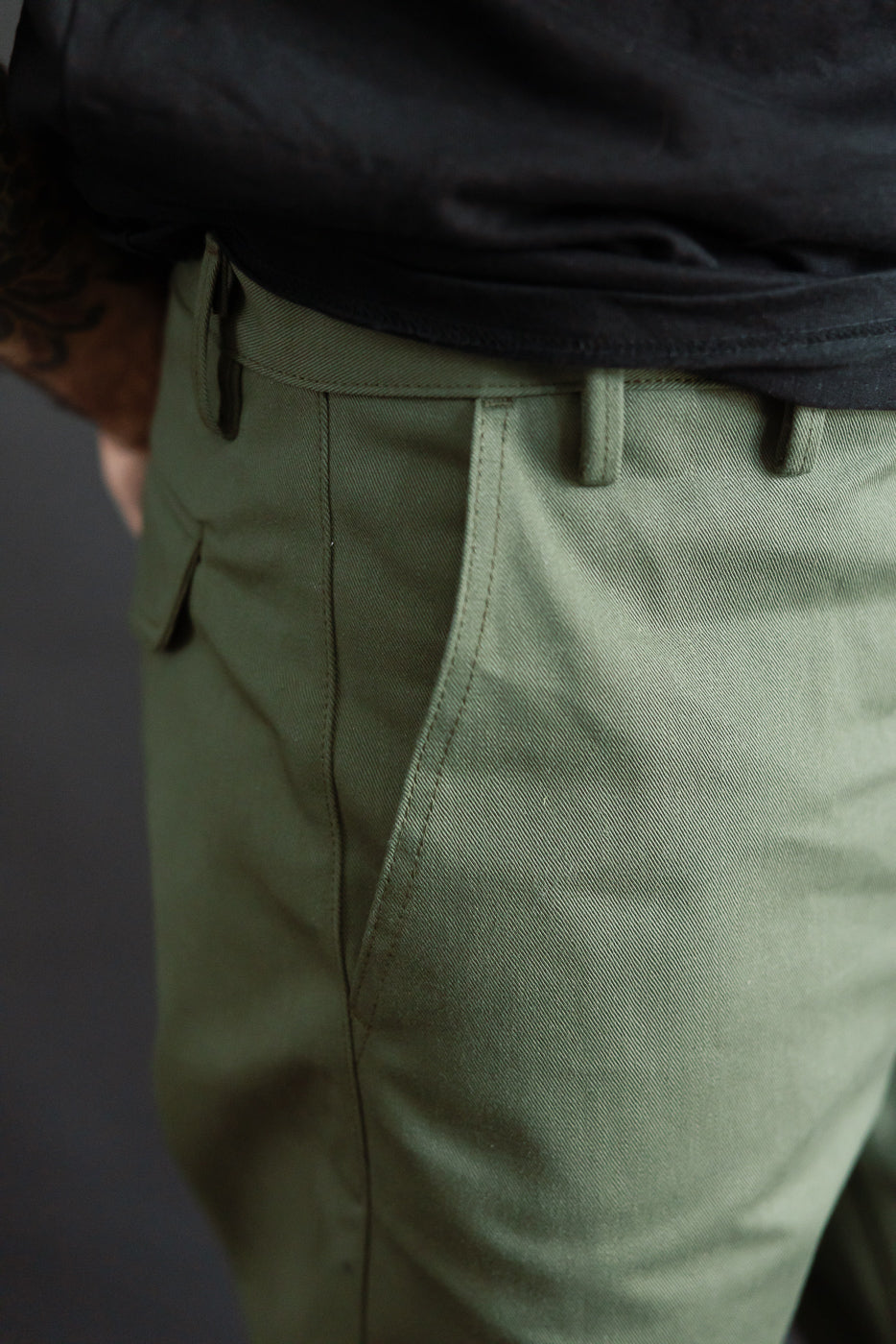Close-up of olive green officer high trouser front pocket, male model, fabric texture detail