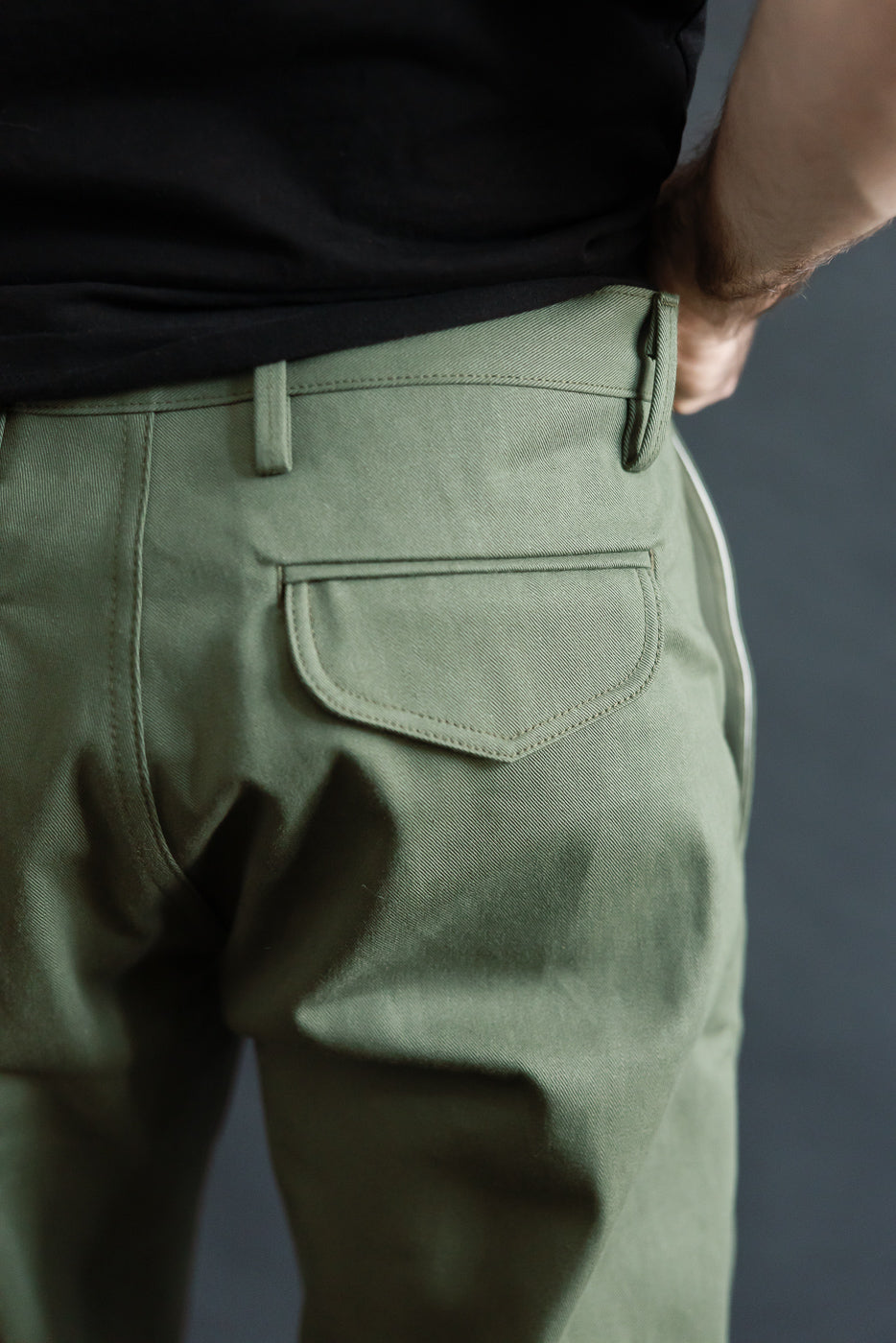 Close-up rear view of olive green officer high trouser on male model, showing back pocket details. Model is 5'9