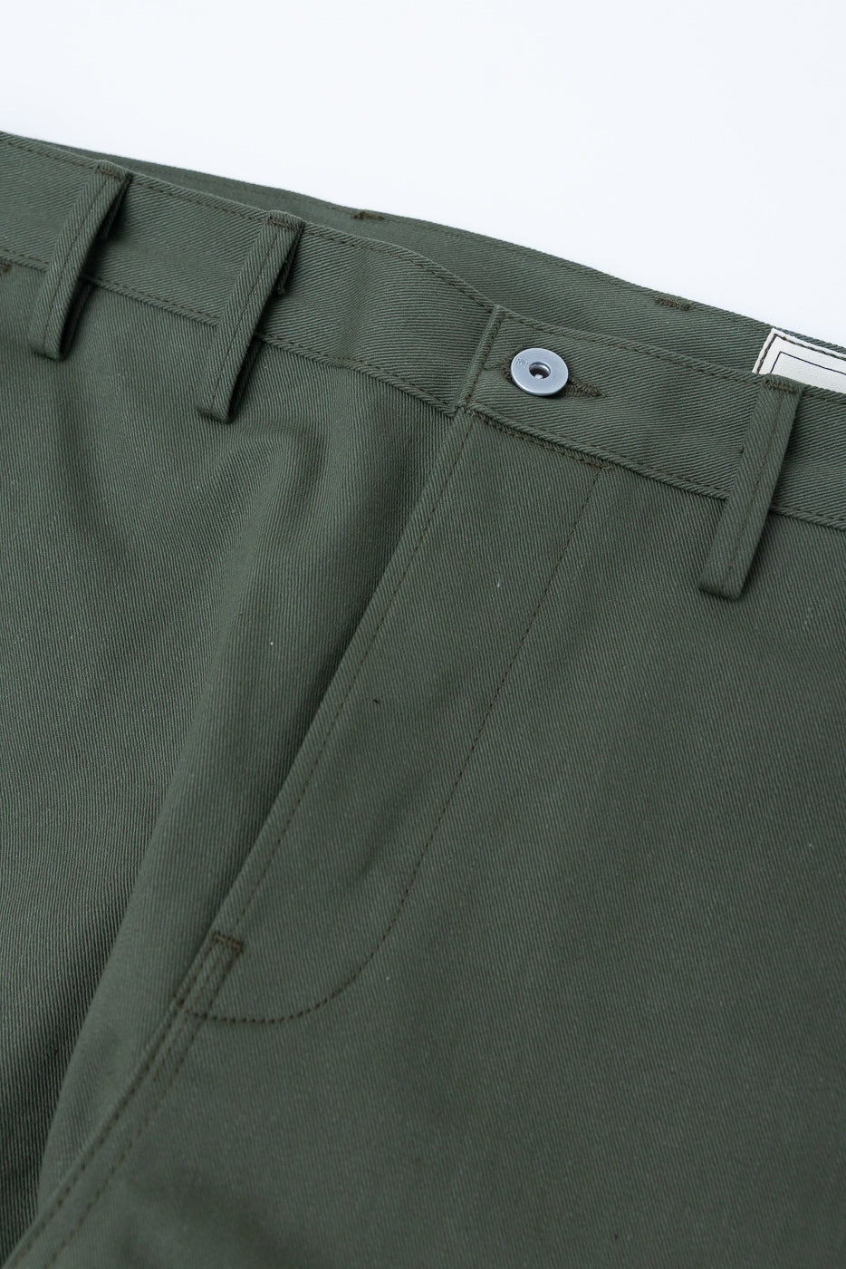 Close-up of front waistband and pocket on olive green men's trousers, showing button and belt loops