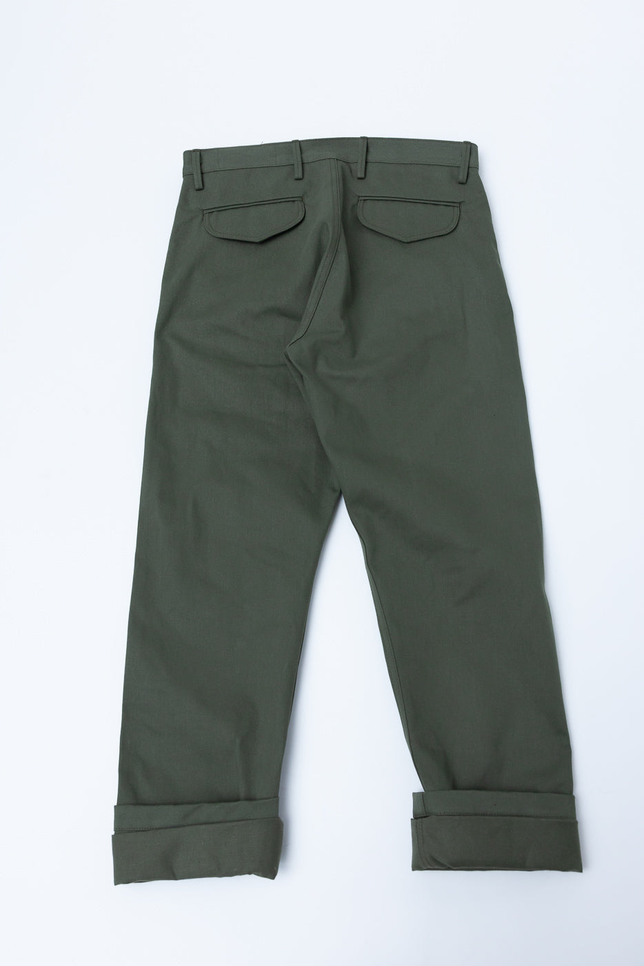 Flat lay of olive green trousers, back view, showing flap pockets and cuffed hems.