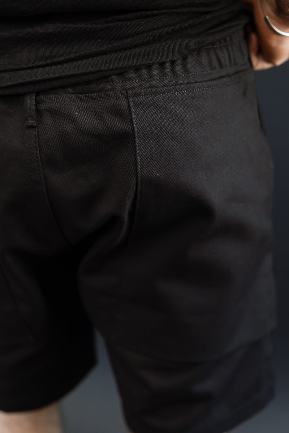 Close-up back view of black shorts on male model, 5'9