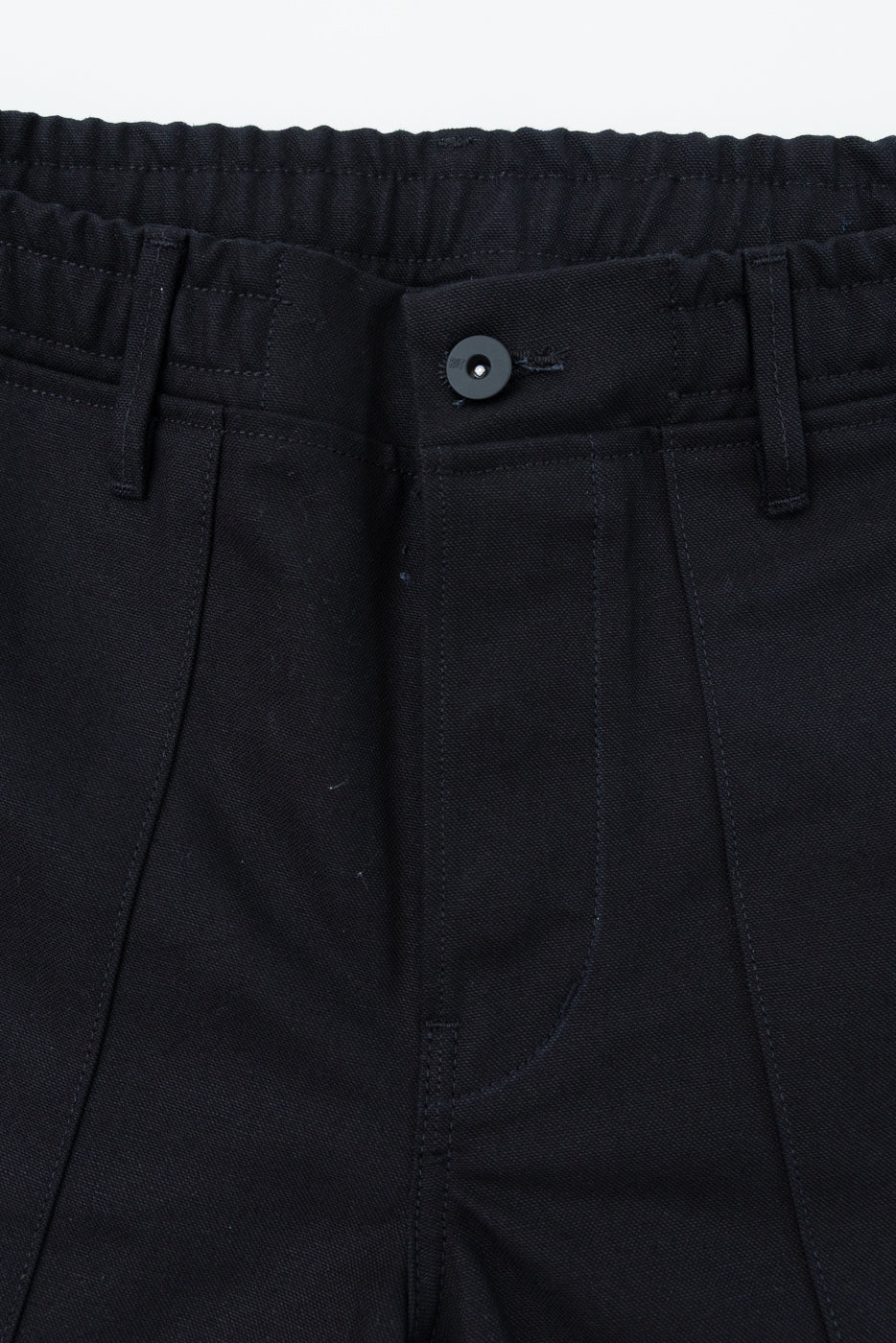 Close-up front view of black pants with button and elastic waistband, showcasing fabric texture and stitching details.