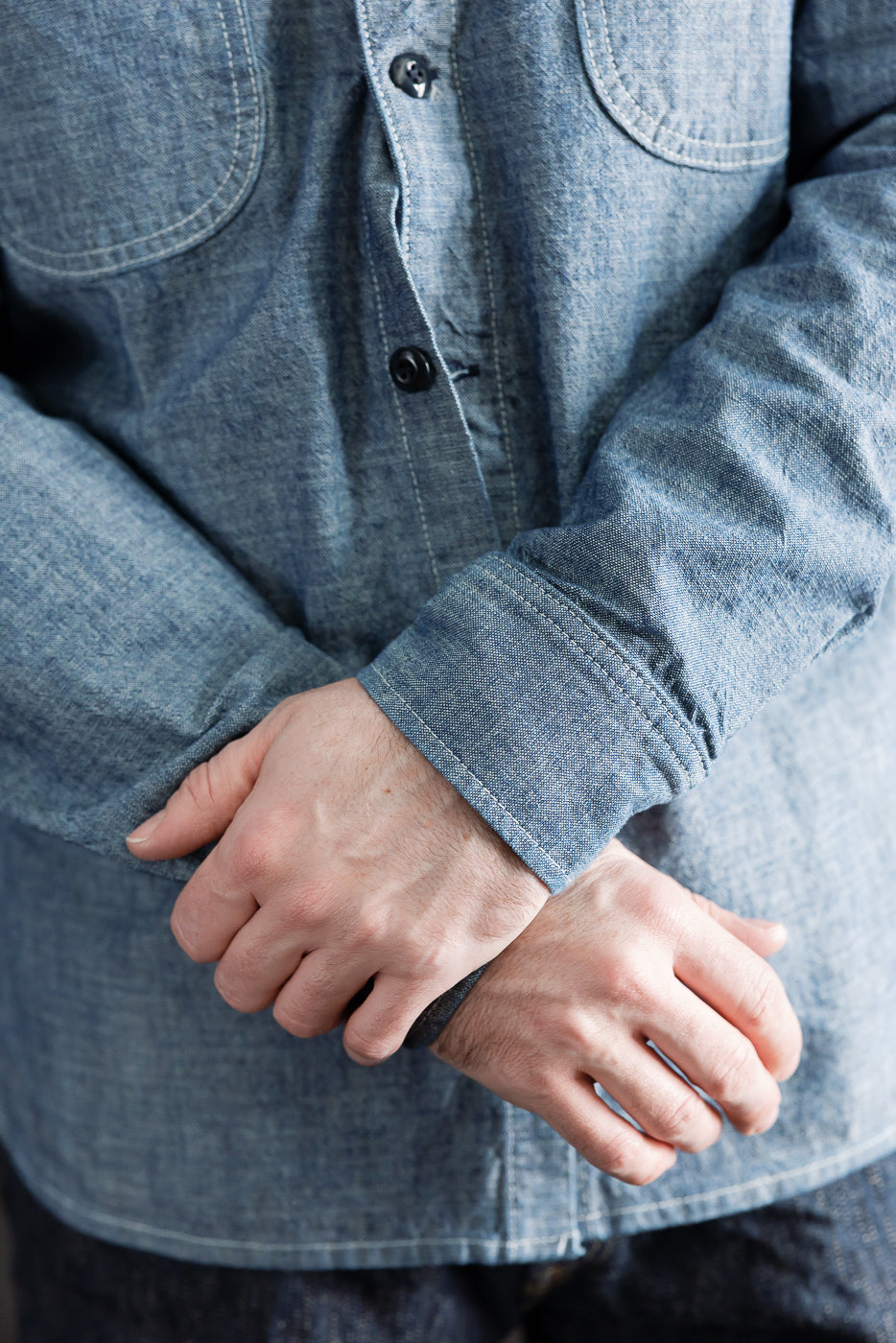 Close-up front of rinsed indigo canvas work shirt on 5'9 male model, cuff and button detail.