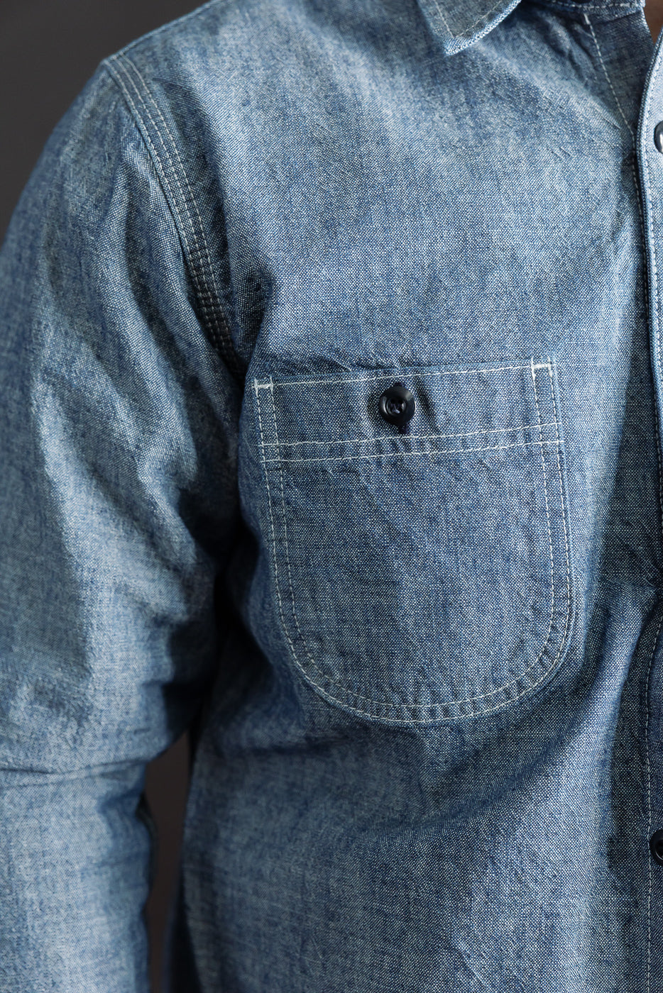 Close-up of Rogue Territory 12oz rinsed indigo canvas work shirt, front chest pocket detail, visible button and fabric texture on male model, Dant contemporary casual apparel.