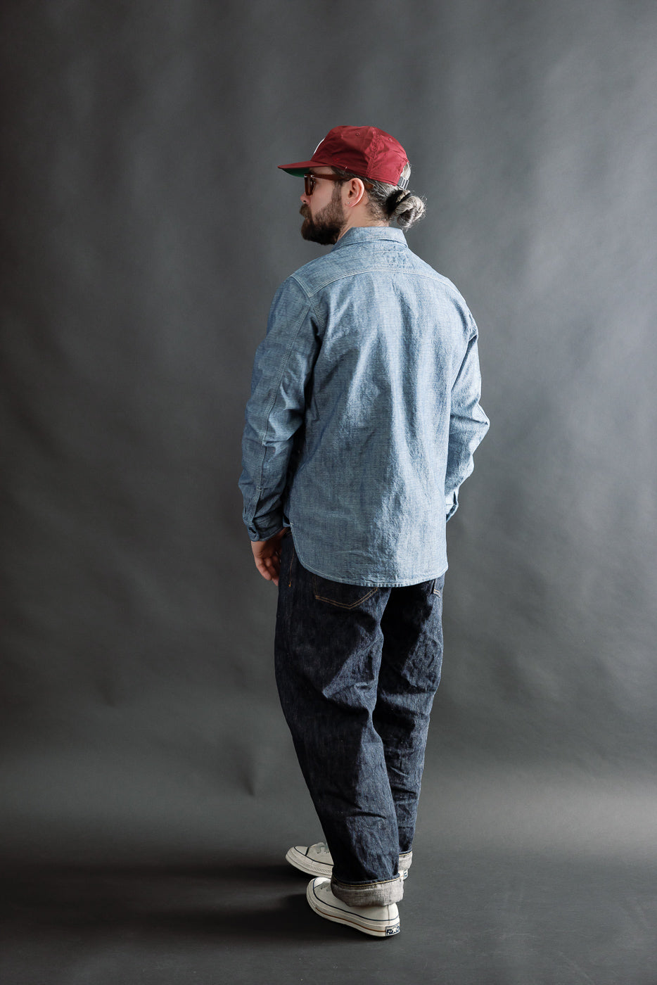 Male model 5'9” 165lbs athletic build wearing light blue button-up work shirt, back view, full body