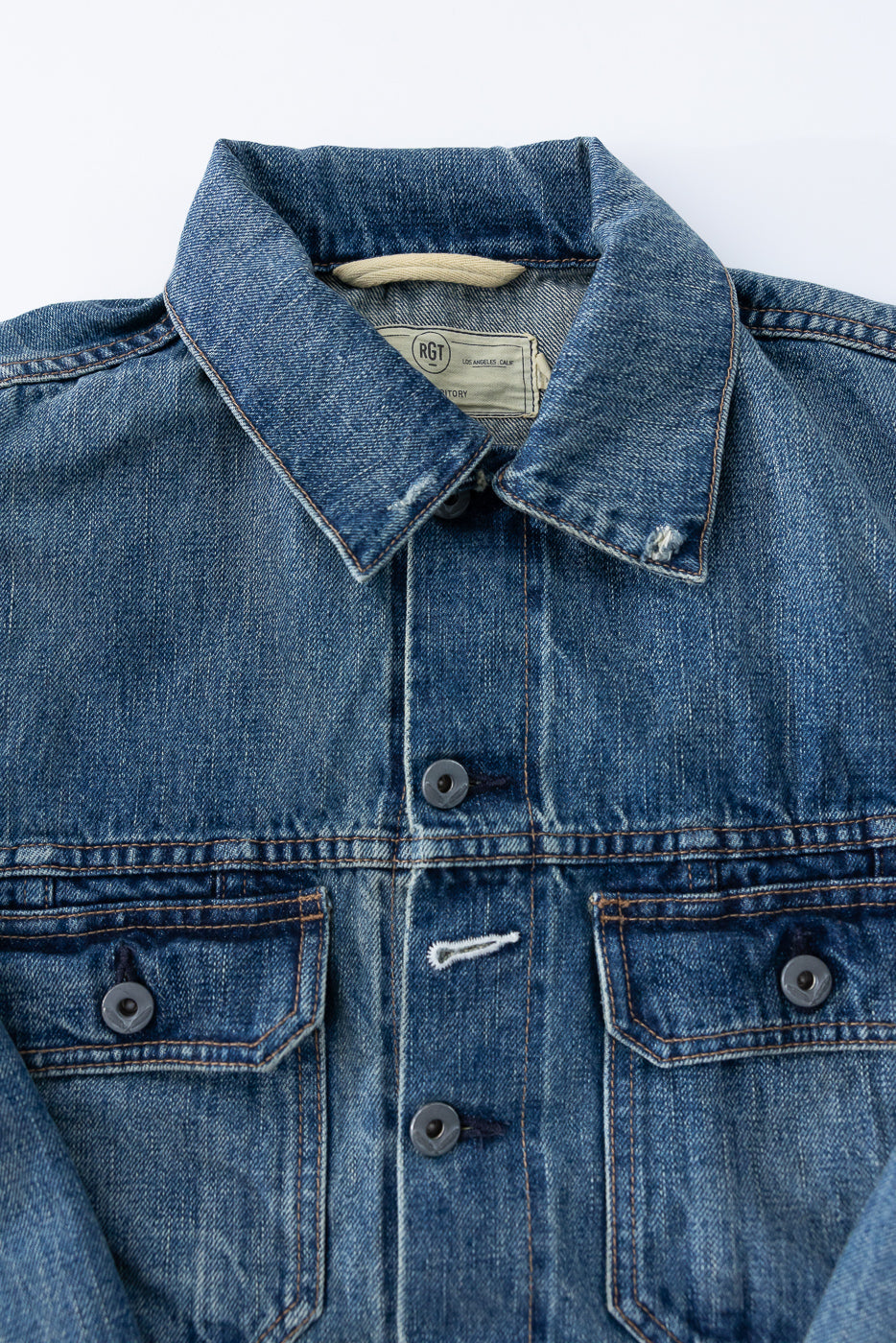 Close-up front view of men's denim jacket showing collar, buttons, chest pockets, and RGT tag detail