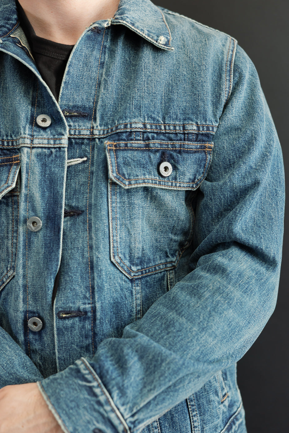 Close-up front view of male model in denim jacket, showcasing chest pocket, buttons, and fabric texture.