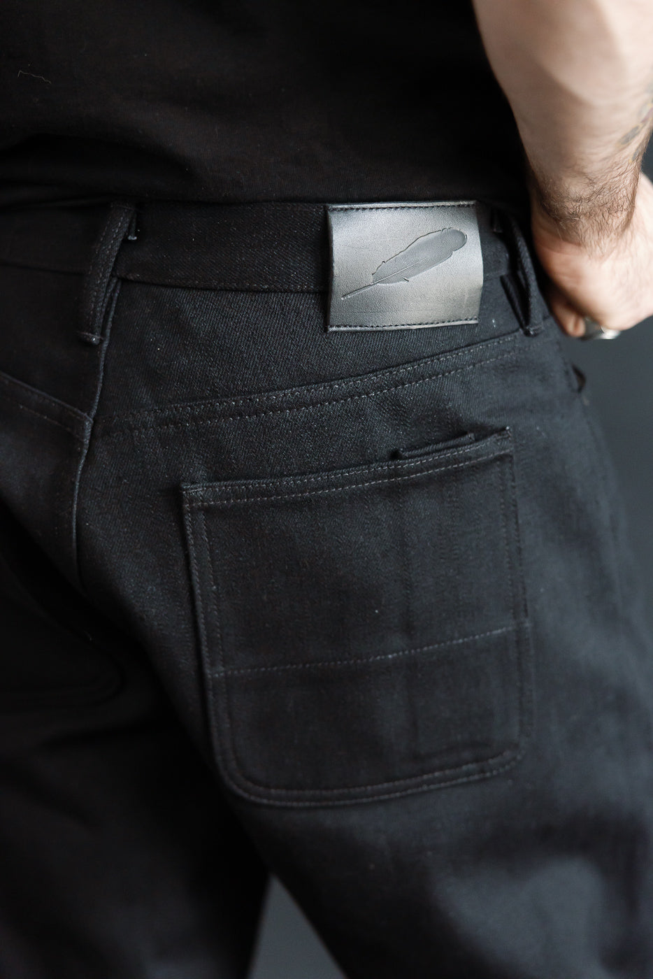 Close-up of the back right side of black selvedge jeans on a male model, 5'9