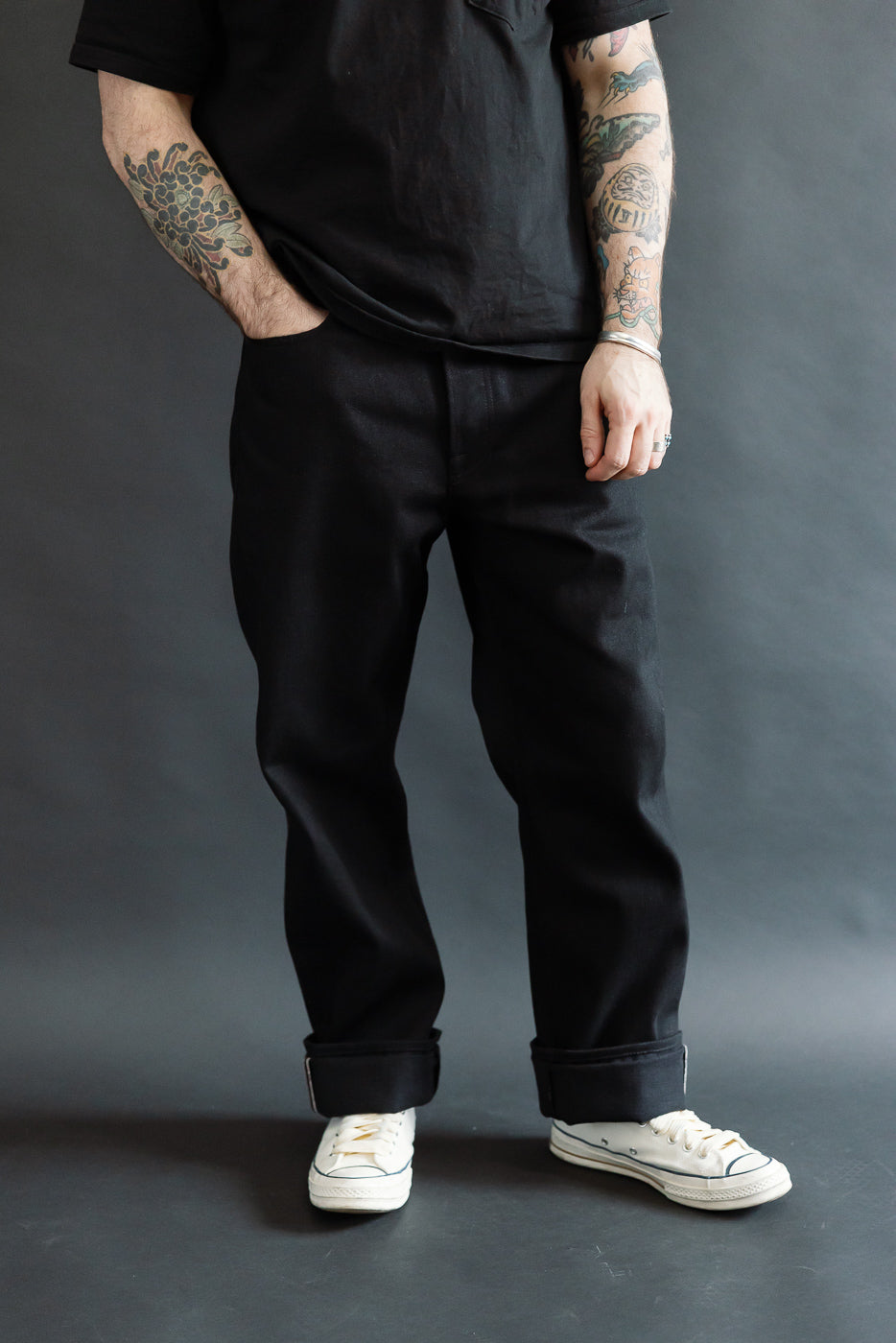 Front full body view of relaxed black selvedge jeans on male model, 5'9