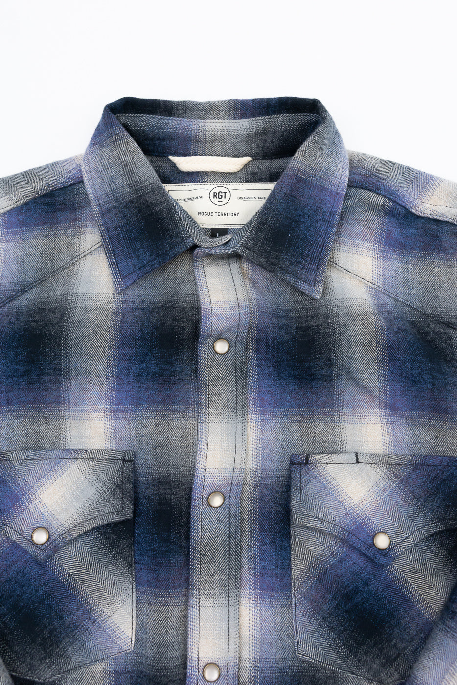 Front view flat lay of a blue and grey plaid flannel shirt showing collar and button placket.