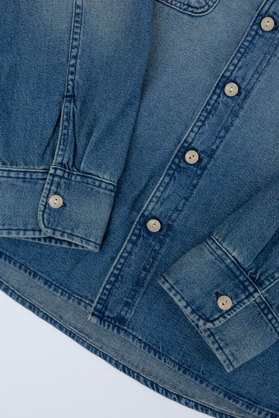 Close-up front view of men's denim shirt showing button placket, chest pockets, and hem detail
