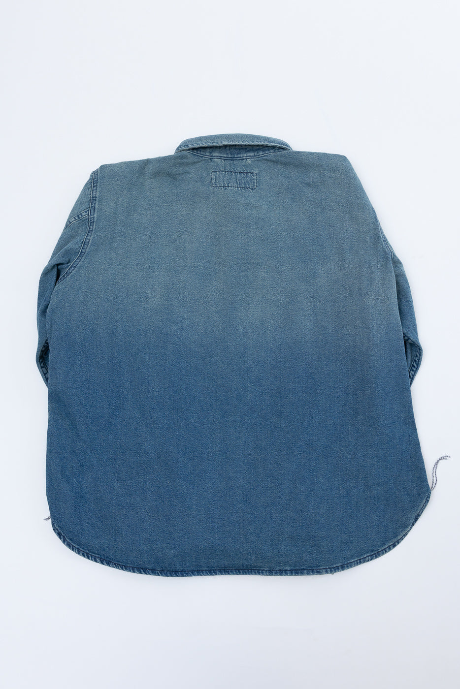 Back view of denim shirt flat lay, showcasing collar, hem, and fabric texture