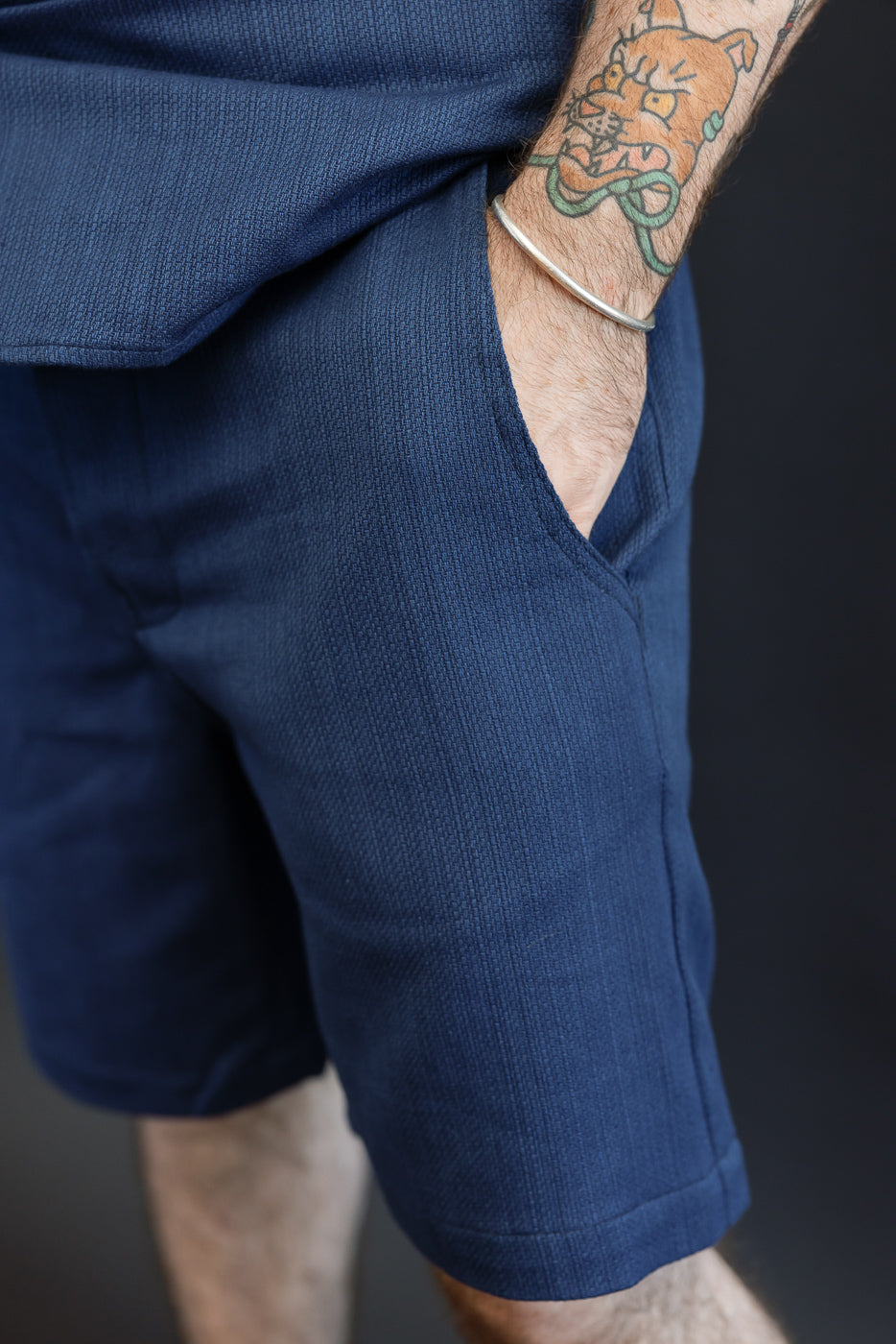 Close-up of navy shorts front, showing texture and side pocket, worn by male model 5'9