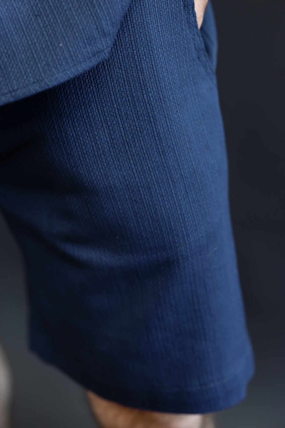 Close-up of navy blue ribbed shorts, front view, worn by male model, showcasing fabric texture and hem.