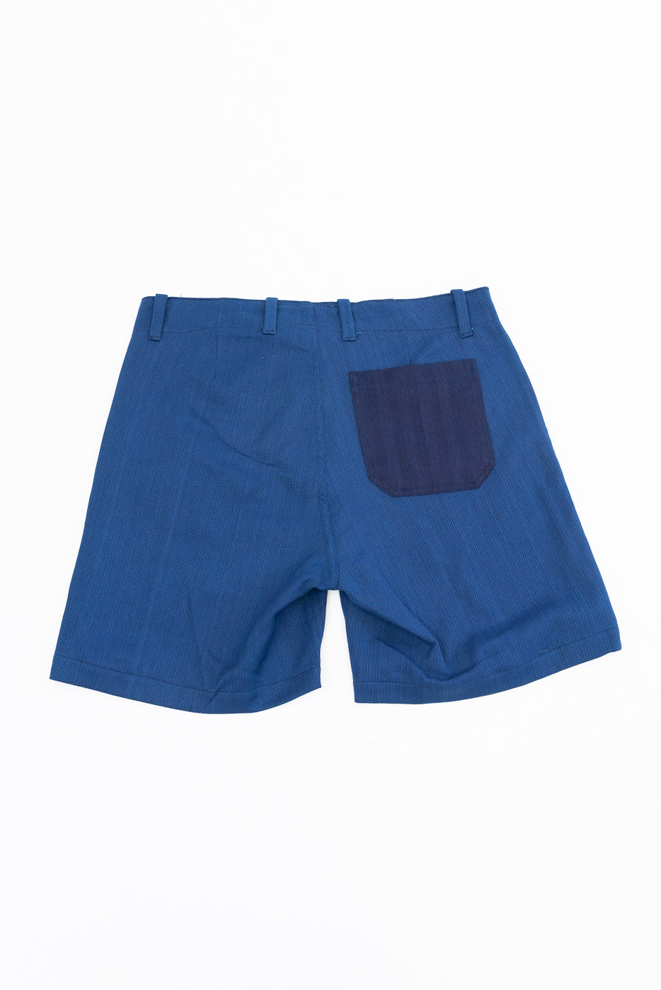 Back view of blue textured shorts with dark patch pocket, flat lay